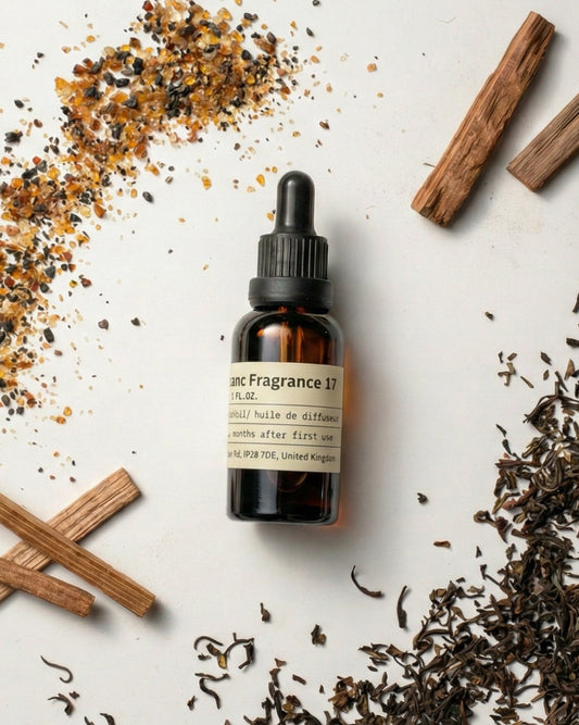 Chavanc Fragrance NO.17 Winds of Darjeeling essential oil bottle surrounded by loose black tea leaves, guaiac wood sticks, and amber resin grains.