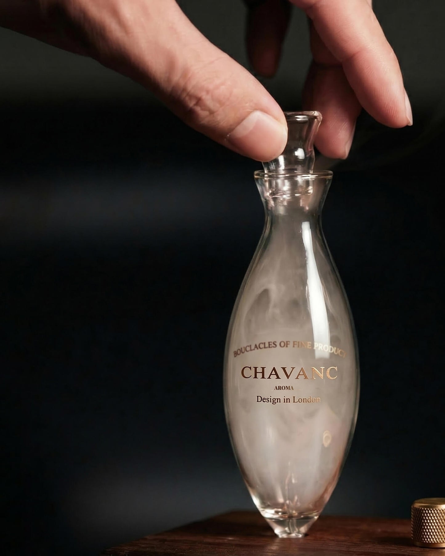 Hand holding a clear bottle labeled 'Chavanc' against a dark background