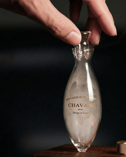 Hand holding a clear bottle labeled 'Chavanc' against a dark background