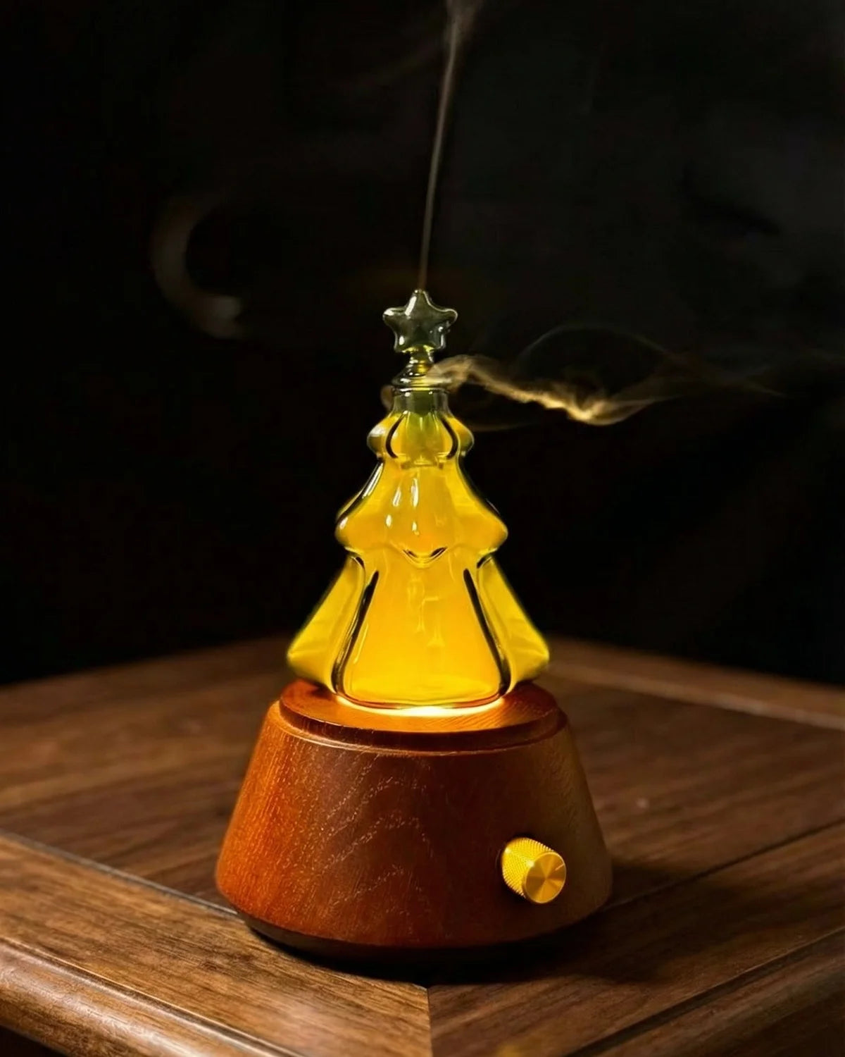 "A warm, detailed close-up of the Chavanc Aroma waterless nebulizing diffuser. The delicate hand-blown glass nebulizer is positioned next to a glowing Edison-style filament bulb, both mounted on a solid dark wood base with a knurled metallic dial. highlighting the artisanal quality."