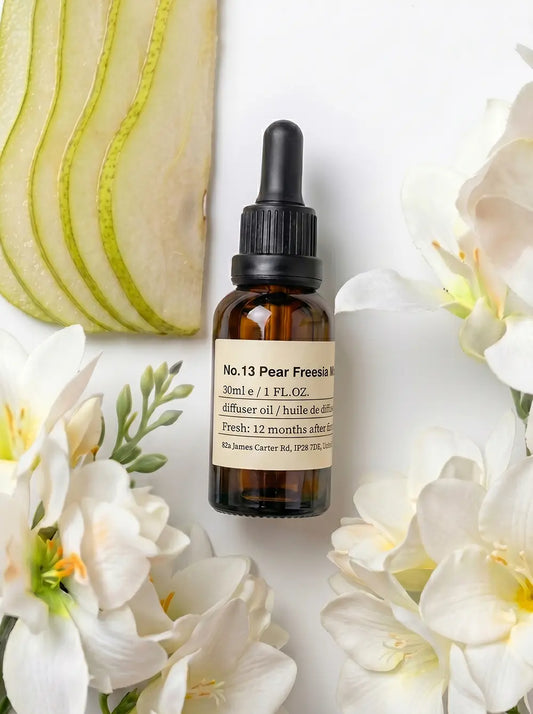 Chavanc Aroma NO.13 Pear Freesia Whisper essential oil bottle displayed with elegant white freesia flowers and green leaves on a clean white background.