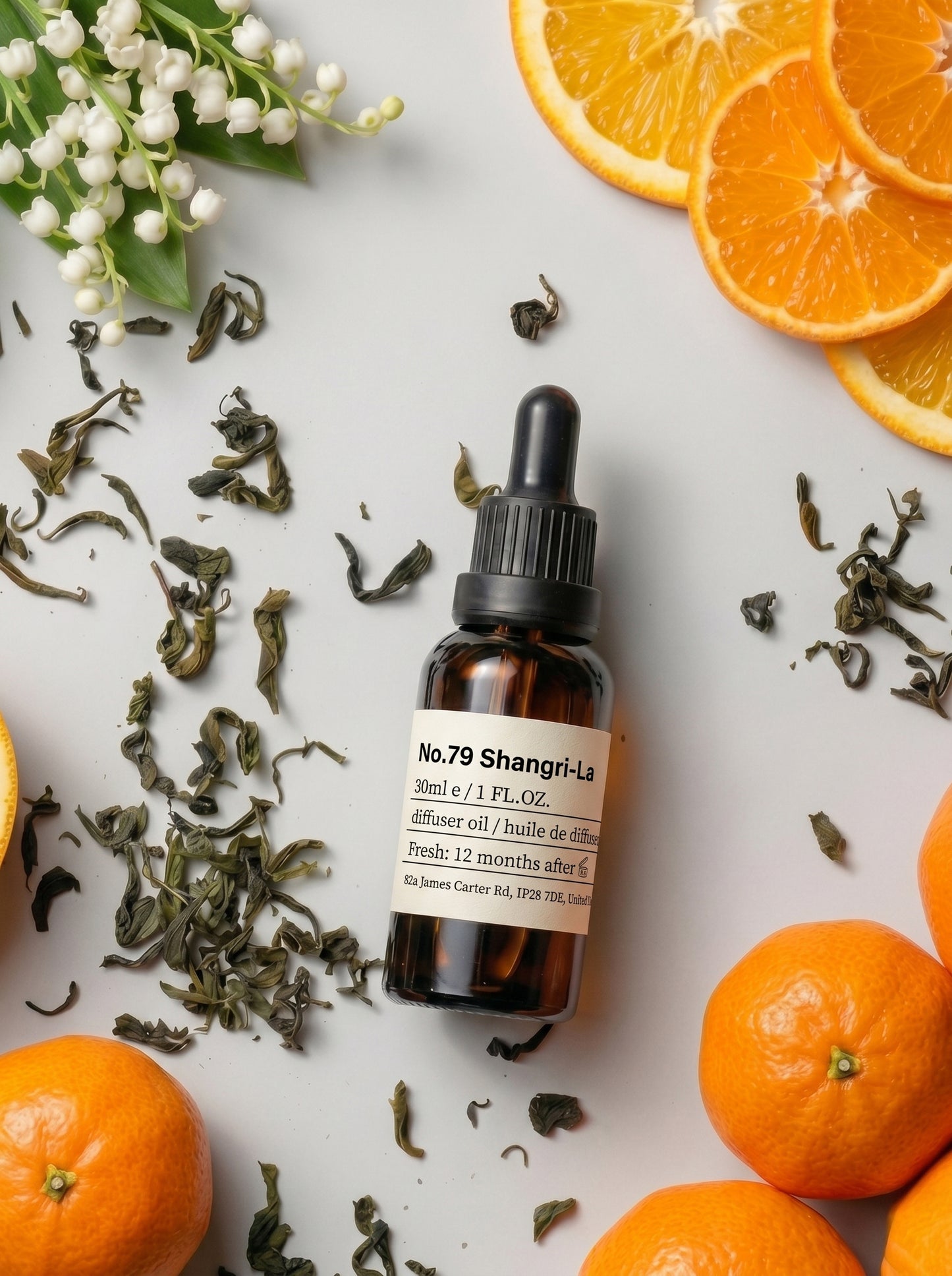 A bottle of NO.79 Shangri-La Essential Oil by Chavanc Aroma featuring citrus and bamboo notes, displayed with fresh lemons, oranges, tea leaves, and bamboo stalks.
